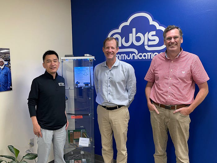 Three team members posing at Nubis Communications office.