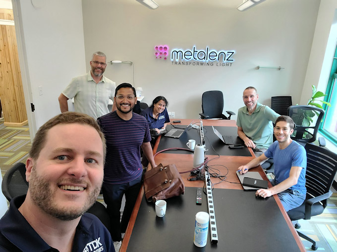 Smiling colleagues gathered around a conference table at Metalenz office.