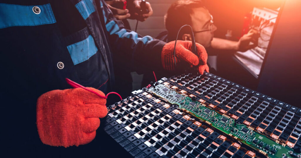 Technician in gloves repairing a circuit board on a workbench.