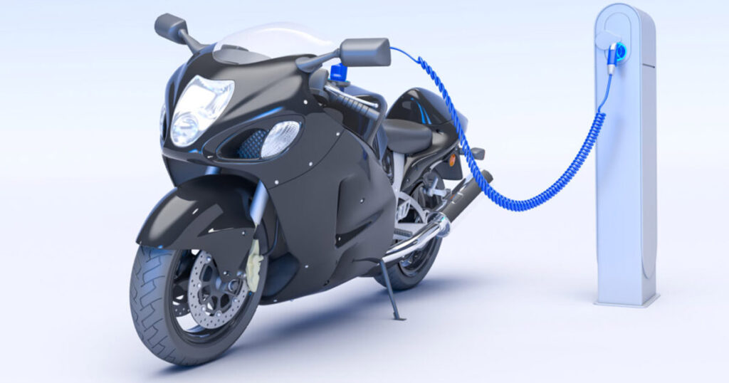 Electric motorbike connected to a charging station with a blue cable.