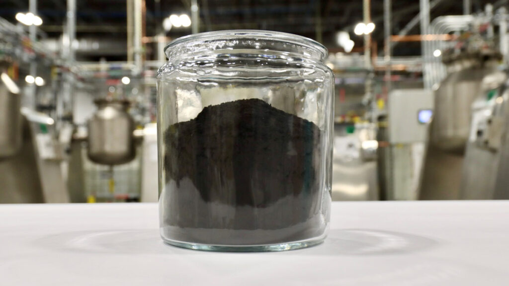 Glass jar with black substance on factory background.