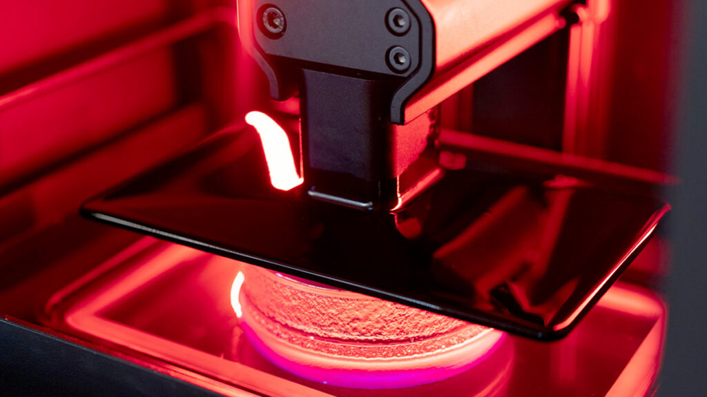 3D printer creating object with red light.