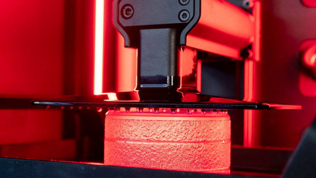 3D printer with red glowing filament.