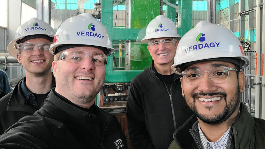 Four workers in hard hats at an industrial plant.