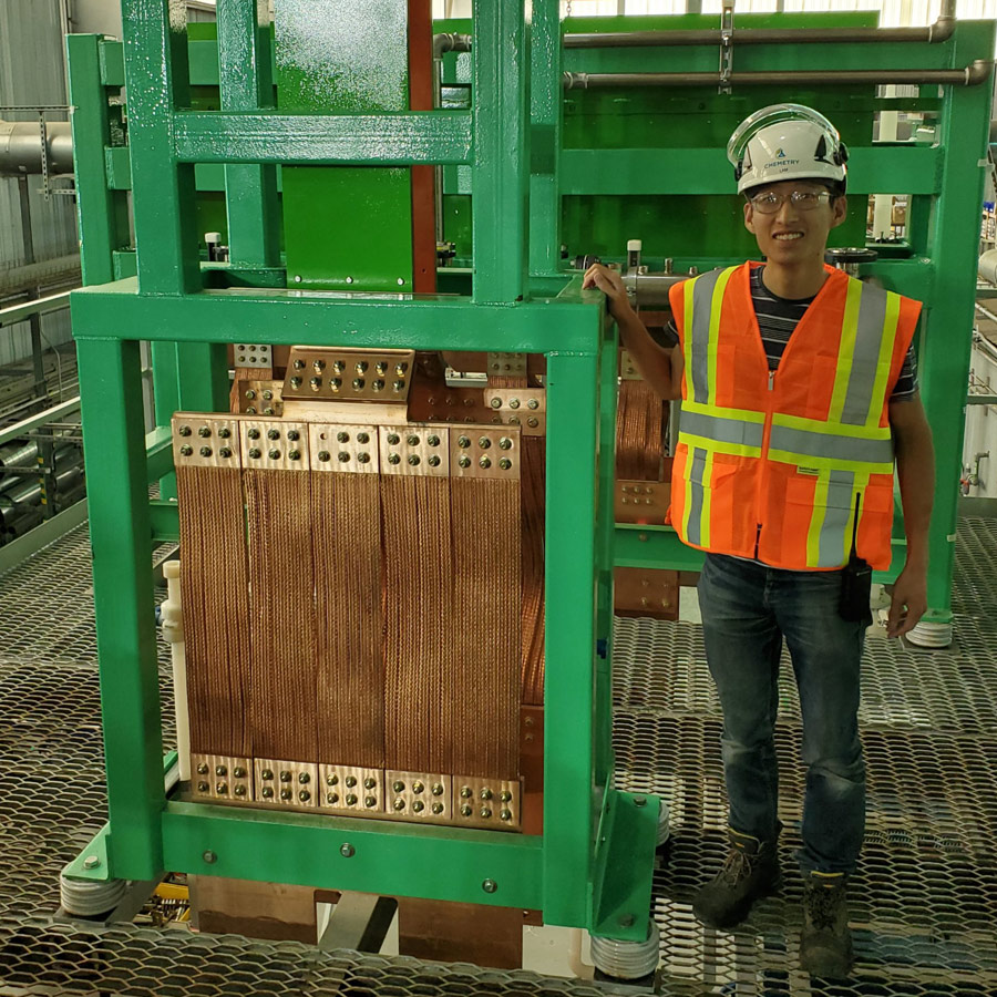 Worker with safety gear by industrial machine.