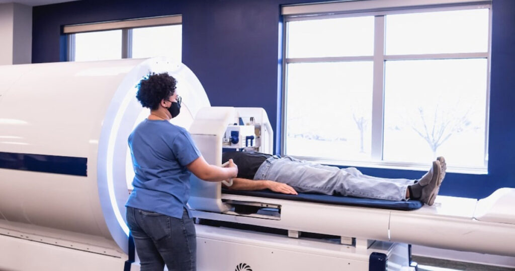 Healthcare professional operates an MRI machine with a patient lying inside.