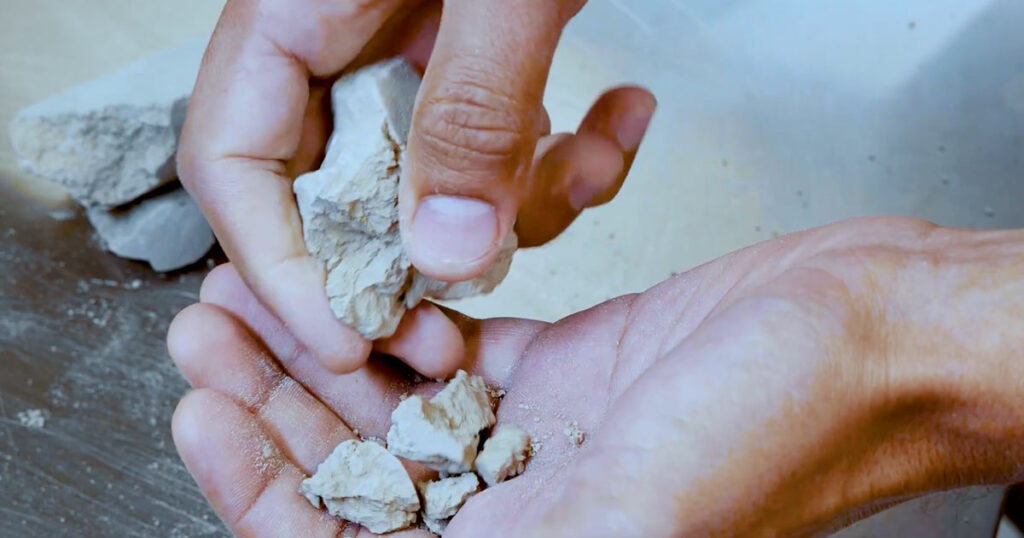 Close-up of a hand holding a piece of white clay.