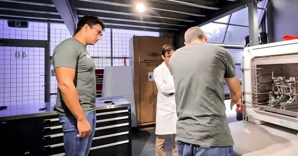 Engineers collaborating near a Novalith industrial 3D printer in a workshop setting.