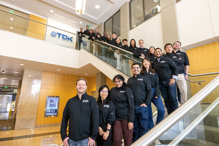 TDK Ventures staff in branded attire posing on stairs inside the office lobby.