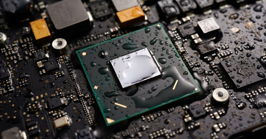 Close-up of a wet microprocessor on a circuit board, indicating potential water damage.