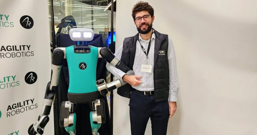 Man standing next to a Digit bipedal robot by Agility Robotics.