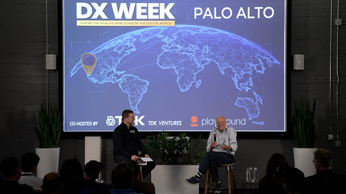 Speakers at DX Week conference in Palo Alto with a digital world map backdrop.