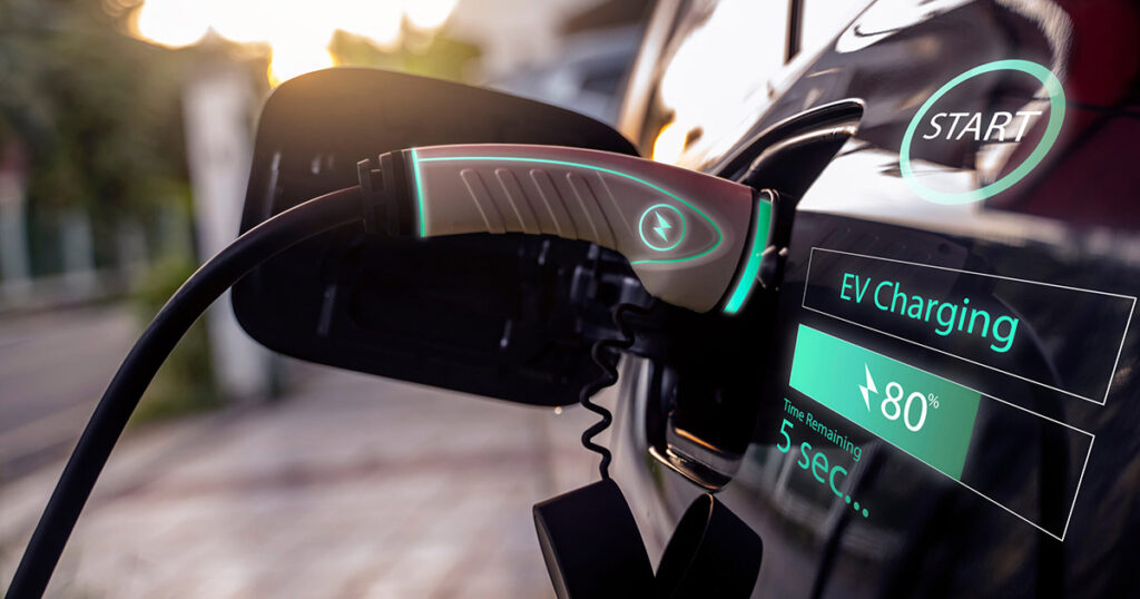 Electric car plugged into a charging station with a digital display showing charge status.