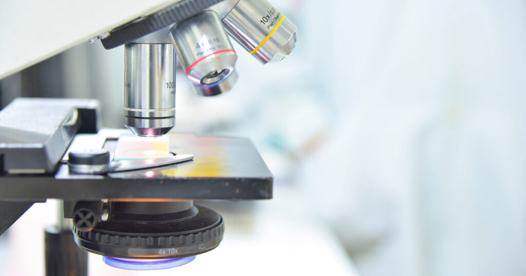 Close-up of a microscope in a lab, highlighting the lenses and stage.