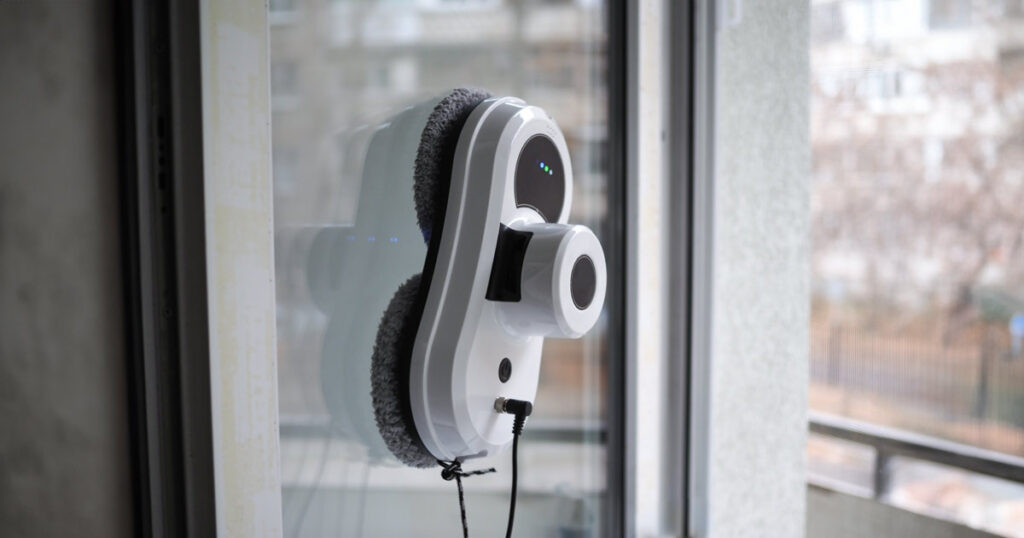 Automatic window cleaning robot operating on a glass surface indoors.