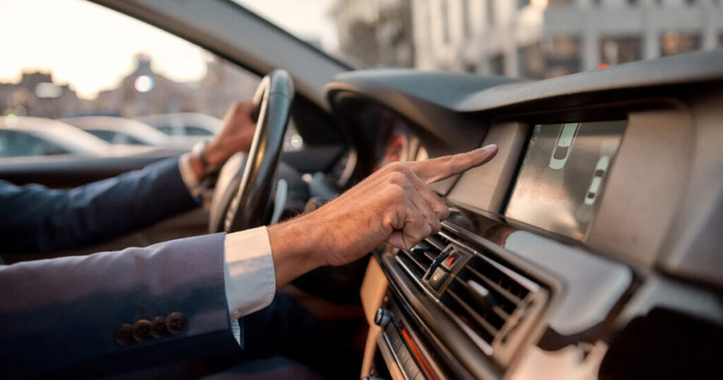 Man adjusting car's infotainment system while driving.