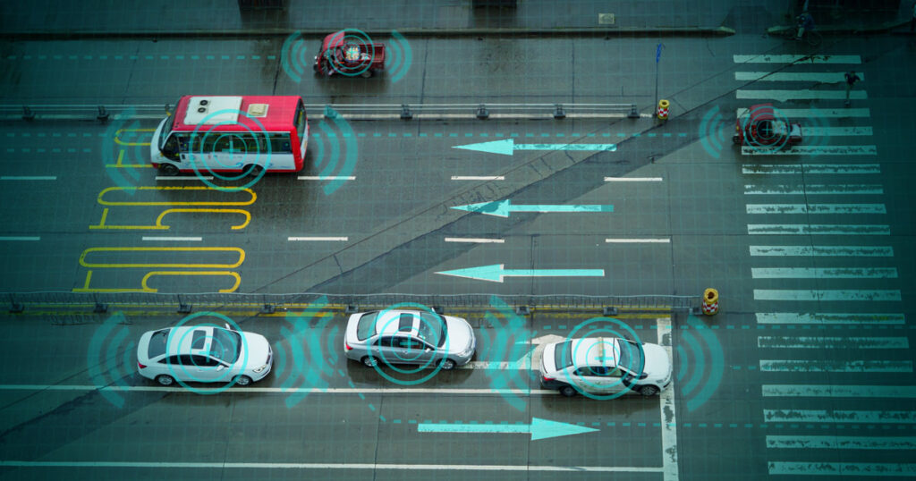 Aerial shot of cars on wet city streets with vivid traffic markings.