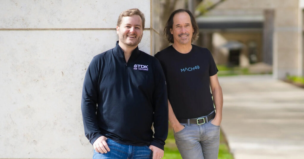 Two tech entrepreneurs smiling outdoors near a building.