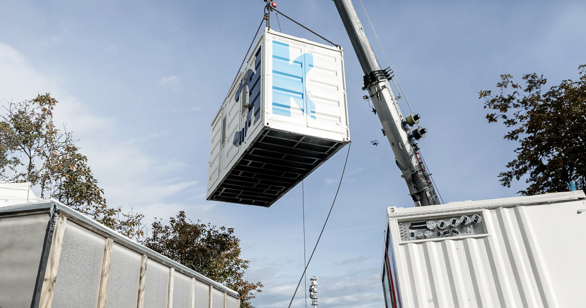 Crane lifting a shipping container onto a stack at a freight yard.